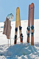 Two wooden skis, sweater and helmet in snow
