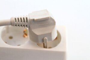 Close-up of plug on extension board against white background