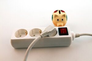 Close-up of triple plug extension with piggy bank on white background