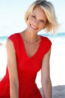 blonde Frau mit rotem Top am Strand