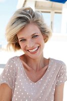Portrait of happy blonde woman with short hair wearing polka dots dress, smiling