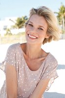 Portrait of happy blonde woman with short hair wearing polka dots dress, smiling