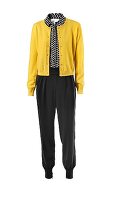 Yellow sweater over polka dot blouse and silk pants against white background