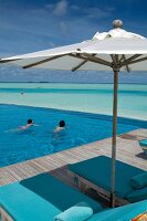 Parasol at swimming pool in front of sea, Dhigufinolhu island, Maldives