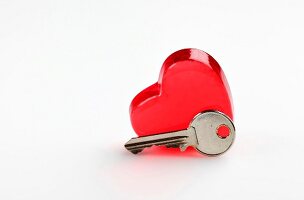 Close-up of red heart shaped glass and key on white background representing valentines day