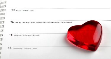 Red glass heart on calendar with date of 14th February