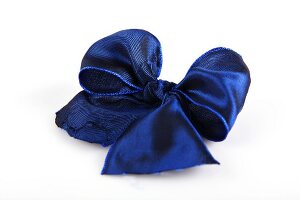 Blue shiny ribbon bow on white background