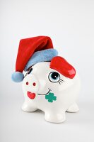 Close-up of piggy bank with red head warmer against white background
