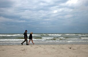 Side view of couple walking on Fano beach, Denmark 