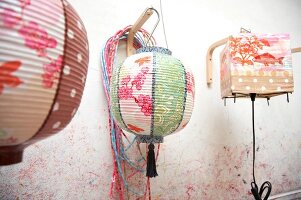 Close-up of person painting colourful lantern with flower and fish motif