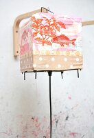 Close-up of person painting colourful lantern with flower and fish motif