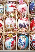 Colourfully painted Easter eggs in a seedling tray lined with straw