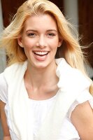Portrait of beautiful blonde woman with long hair wearing white sweater, smiling