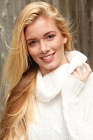 Portrait of beautiful blonde woman with long hair in white turtleneck sweater, smiling