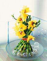 Close-up of yellow orchids with lucky bamboo sticks in bowl
