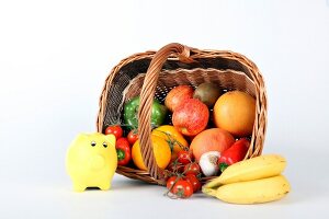Obstkorb, umgekippter Bastkorb mit Obst und Gemüse