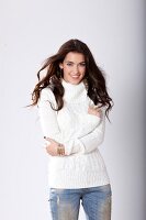 Portrait of pretty woman with dark hair in white turtleneck sweater and jeans, smiling