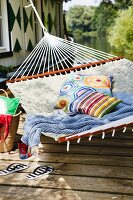 Hammock with colourful cushions & blanket outside boathouse