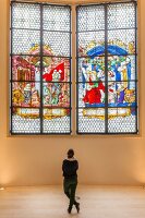 Woman standing in front of Kaiser window, Augustiner Museum, Freiburg, Germany