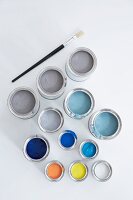 Blue, grey, black, white and yellow paint in colour pots on white background