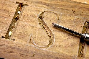 geschnitzte Buchstaben in einem Holzbrett