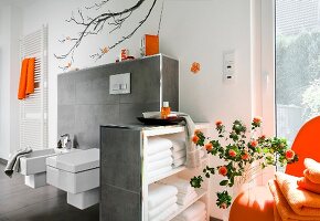 Luxurious bathroom with sink, large windows and orange accessories