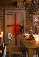 A wooden door decorated with a bow and a stocking with a sprig of mistletoe hung with Christmas decorations above a table in the foreground