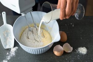 Sugar being added in mix baking ingredients in bowl for preparing waffle