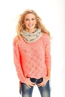 Portrait of pretty blonde woman wearing apricot colour sweater and scarf, smiling