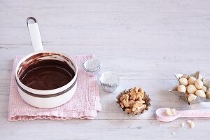 Stillleben mit Nüssen, Pralinenförmchen & flüssiger Schokolade