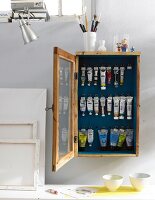 Canvases and a wooden wall cupboard for storing paint tubes