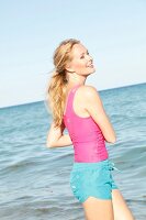 Blonde, sportliche Frau mit Pferdeschwanz am Strand