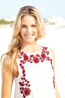 Blonde woman with long hair in a summer dress on the beach