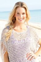 Blonde woman with long hair in a crochet shirt on the beach