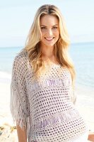 Blonde woman with long hair in a crochet shirt on the beach