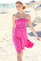 Blonde Frau mit Zopf im Kleid am Strand