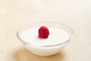 Vanilla cream in a bowl topped with a raspberry