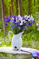 Blaue und weiße Iris im Krug auf Holztisch