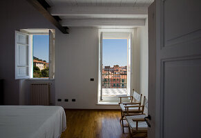 Simple bedroom with wooden floor and view of the city