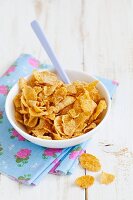 Cornflakes in a ceramic bowl with a spoon on a colourful napkin