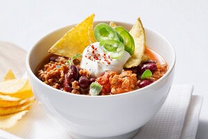 Chili con carne with sour cream and tortilla chips