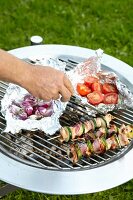 Meat kebabs, onions and tomatoes on a barbecue