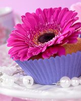 A muffin topped with a gerbera flower