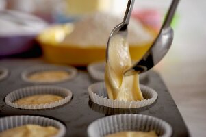 Cupcake mixture being spooned into paper cases