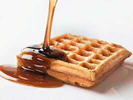 Maple syrup being poured on to waffle