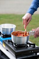 Chilli with mushrooms in a pot on a camping stove