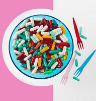 Lots of colourful tablets on a plate with plastic forks next to it