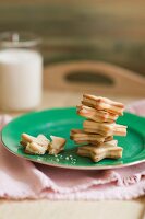 Frosting Filled Star Shaped Cookies on a Plate, One Broken; Glass of Milk