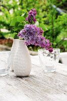 Purple lilac in vase on garden table