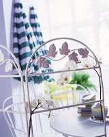Paravent aus weißem Metall mit Blumendekor vor Gartentischgarnitur